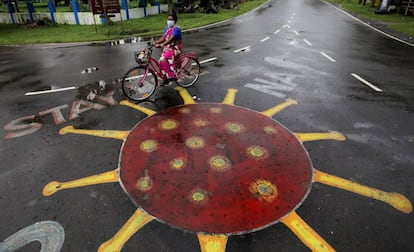 En India, las ONG antitrata se han visto desbordadas para poder ayudar a las supervivientes durante la pandemia. En la imagen, una mujer pedalea junto a un dibujo del SARS-CoV-2 pintado sobre el asfalto en Calcuta, India.
