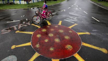 En India, las ONG antitrata se han visto desbordadas para poder ayudar a las supervivientes durante la pandemia. En la imagen, una mujer pedalea junto a un dibujo del SARS-CoV-2 pintado sobre el asfalto en Calcuta, India.
