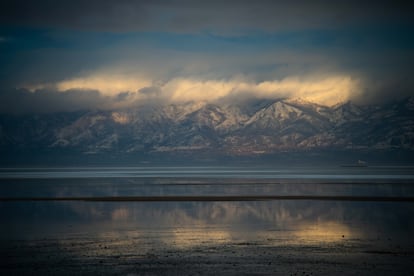 Light reflects off the surface of the lake. Kennecott Copper Mine is seen in the background.