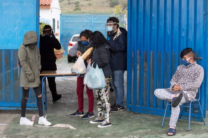 Patxi Velasco, en el centro con mascarilla, durante el reparto de comida entre vecinos de la barriada de Los Asperones en el colegio público María de la O, este jueves.