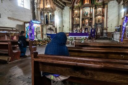 Un hombre y una mujer rezando el rosario en la iglesia de Nurio. 