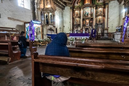 Un hombre y una mujer rezando el rosario en la iglesia de Nurio.