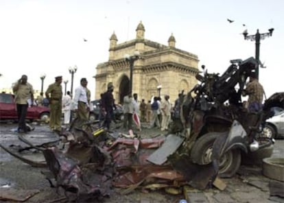 Policías y viandantes, ante un vehículo destrozado por la explosión en la Puerta de India, ayer en Bombay.