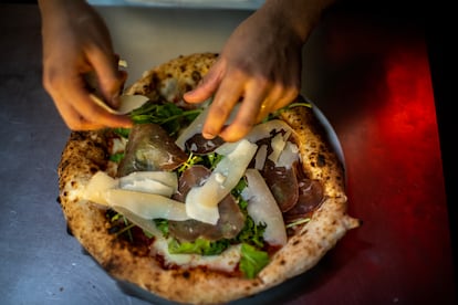 Un cocinero da los últimos toques a la pizza.