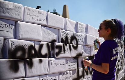 Un activista escribe la palabra "Racismo" sobre el muro improvisado durante la marcha de Ciudad de México.