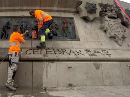 Dos operaris netegen les pintades al monument a Colom.