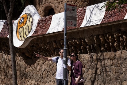 Dos turistas miran el recorrido del bus 116, que ya no aparece en Google Maps, en el poste de la parada del Park Güell de Barcelona.