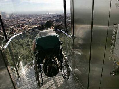 Un joven discapacitado oberva Barcelona tras subir en el ascensor adaptado del Tibidabo.