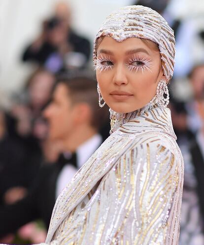 Gigi Hadid
La ceñida capucha de Gigi Hadid, diseño de Michael Kors, daba lugar a un look beauty de lo más llamativo y nuclear creado por Erin Parsons con productos de Maybelline.
Sobre una base con mucho iluminador y labios nude, unas pestañas postizas larguísimas y en color blanco atrapaban todas las miradas.