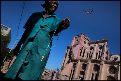 Una mujer con un rosario, junto a la catedral de Puerto Príncipe (Haití), en ruinas tras el terremoto de 2010, que dejó más de 300.000 víctimas. 