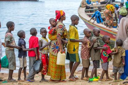Niños y madres haciendo cola para embarcar en el pequeño pueblo de Kagunga.