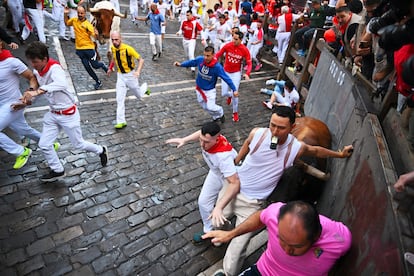 Los mozos avanzan a toda velocidad delante de los toros durante el recorrido del encierro.