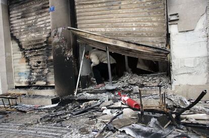 Un empleado sale de un banco incendiado el domingo.