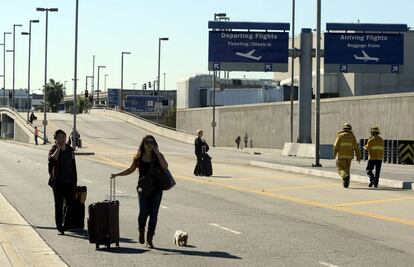 Varias personas caminan en el exterior del del aeropuerto internacional de Los &Aacute;ngeles.