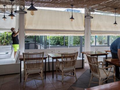 Un empleado de un restaurante limpia las mesas antes de la llegada de los clientes.