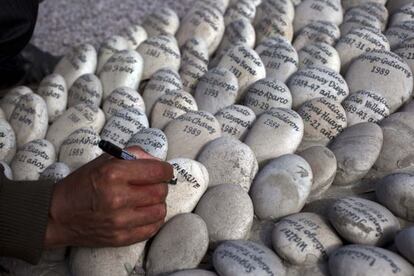 Simeon Irrazabal writes the name of his father, who he said was killed by the Peruvian army in 1987, at the &quot;Ojo que Llora&quot; or &quot;Eye that Cries&quot; memorial in Lima, Peru, Wednesday, Aug. 28, 2013. 