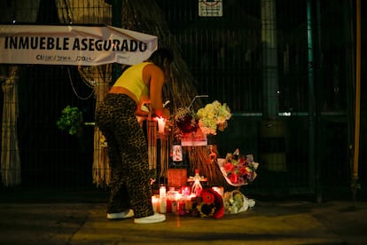 Una mujer enciende una veladora en un altar instalado fuera del bar Los Cantaritos, este domingo en la ciudad de Querétaro.