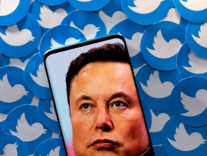 Imagen de Elon Musk en una pantalla sobre pegatinas con el logo de Twitter.