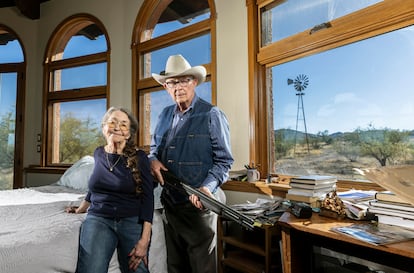 Reportaje sobre Arizona, estado clave en las elecciones estadounidenses de noviembre. Jim y Sue Chilton, octogenarios residentes de un rancho que colinda con la frontera de México, cuentan cómo su propiedad es un paso frecuente para inmigrantes irregulares y, según ellos, también para narcotraficantes que transportan drogas. En la imagen, posan en su dormitorio, donde duermen con una escopeta, mientras al fondo se aprecia su rancho fronterizo.