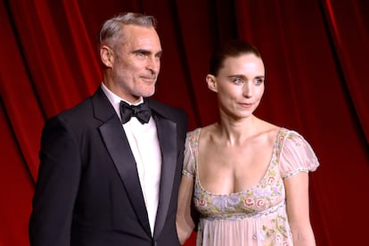 Joaquin Phoenix y Rooney Mara. A pesar de que son una de las parejas más discretas y consolidadas de Hollywood, su historia de amor era más que improbable teniendo en cuenta los orígenes sociales y familiares de cada uno de ellos. Rooney Mara es fruto del matrimonio que unió a dos de las familias más poderosas de Estados Unidos: los Mara son los dueños del equipo de fútbol americano New York Giants y los Rooney poseen los Pittsburgh Steelers, un club no menos histórico en la NFL. La joven nació y creció en una de las comunidades más ricas del país, mientras que su marido, Joaquin Phoenix, actuaba con sus hermanos por las calles de Puerto Rico a cambio de la voluntad de los transeúntes. Sus padres, hippies contraculturales, formaban parte de la secta de los Niños de Dios y fueron acusados de abusos sexuales incluso por niños (el propio hermano del actor, River Phoenix, confesó que había perdido la virginidad a los cuatro años). A pesar de que las vidas previas de ambos se sitúan en las antípodas, han logrado ser una de las parejas más sólidas del 'star system' desde que comenzaran su relación en 2016.