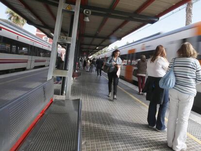 Un grupo de viajeros espera la parada de un tren en un and&eacute;n de Cercan&iacute;as de Renfe.