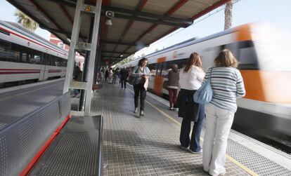 Un grupo de viajeros espera la parada de un tren en un and&eacute;n de Cercan&iacute;as de Renfe.