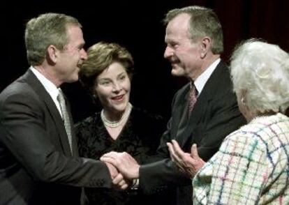 El ex presidente de Estados Unidos George Bush (segundo por la derecha) estrecha la mano de su hijo, el actual presidente, George W. Bush.