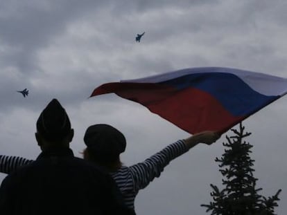 Una mujer ondea una bandera rusa en Sebastopol ante la presencia de aviones rusos en la celebraci&oacute;n del D&iacute;a de la Victoria.