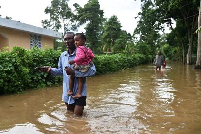 Un hombre camina con una niña en sus brazos por una calle inundada en Malfeti (Haití), el 8 de septiembre.