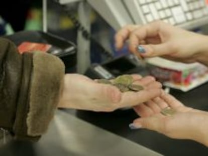 Una cajera ayuda a un cliente a contar las monedas de euro en un supermercado. 