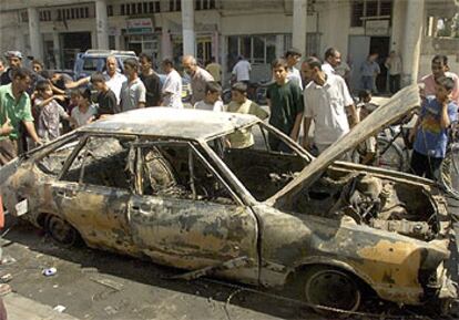 Varias personas observan el estado en que quedó el vehículo contra el que dispararon las tropas de EE UU en Bagdad.