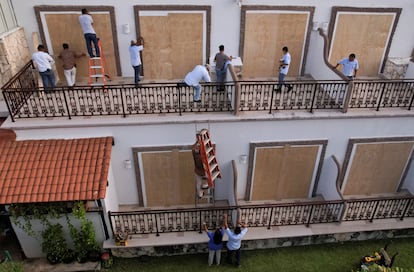 Trabajadores colocan tablones de madera para proteger los ventanales de un hotel en Playa del Carmen, México, este miércoles, antes de la llegada del huracán.