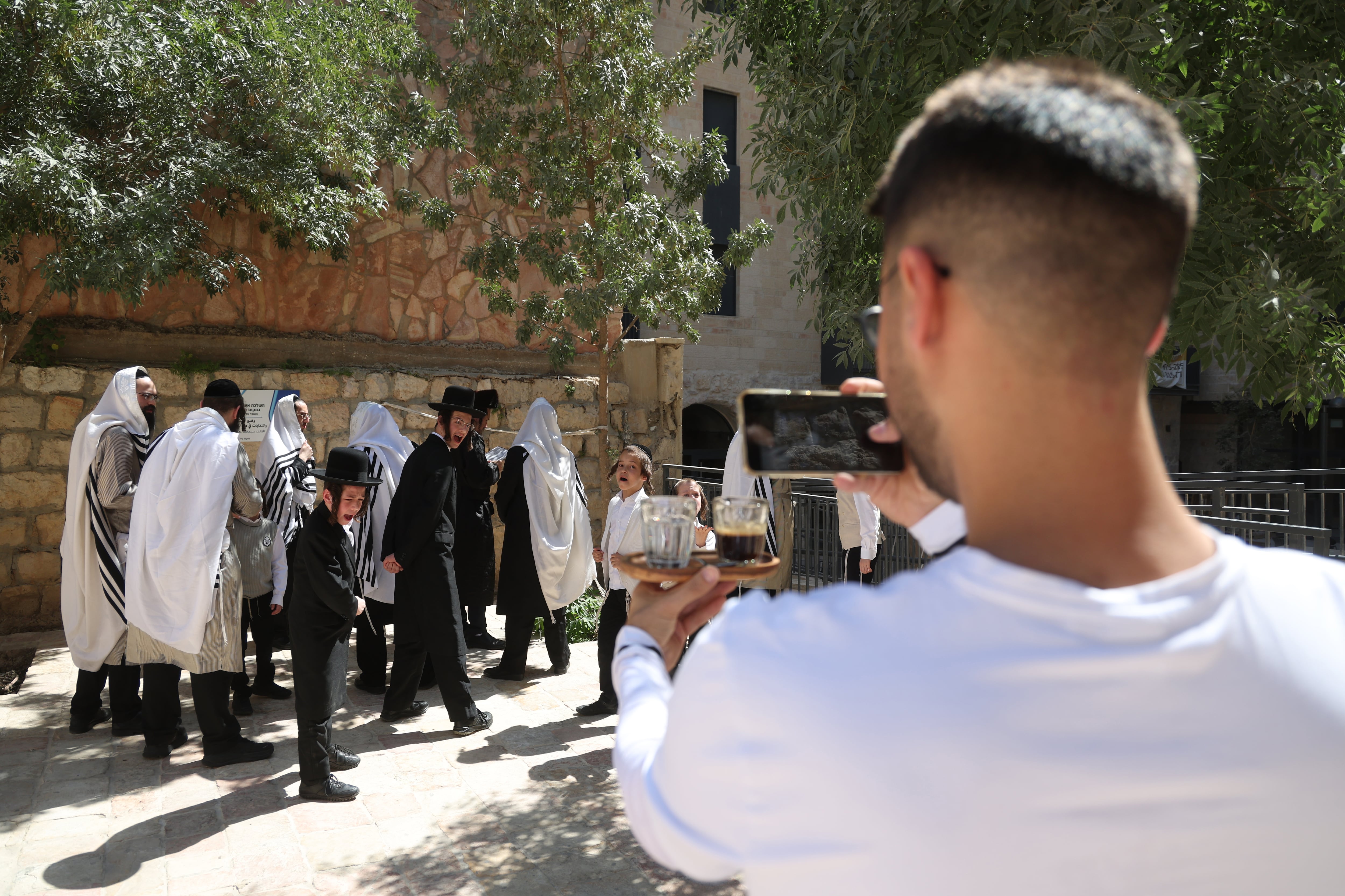 Un contramanifestante secular toma una foto de su café con los manifestantes ulrtaortodoxos de fondo, este sábado en Jerusalén.