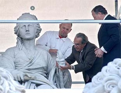 El alcalde de Madrid (dcha), y el escultor Luis Parés colocan en el brazo izquierdo de la Cibeles la reproducción de la mano.