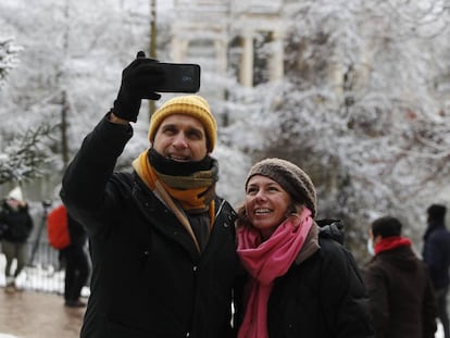 Dos personas se toman una foto en el Retiro, en Madrid, durante la nevada.