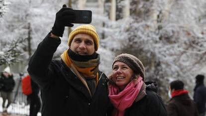 Dos personas se toman una foto en el Retiro, en Madrid, durante la nevada.