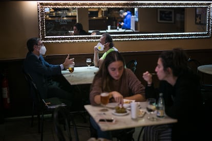 Varios clientes con y sin  mascarillas en un bar de Barcelona, este jueves.