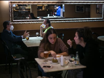 Varios clientes con y sin  mascarillas en un bar de Barcelona, este jueves.