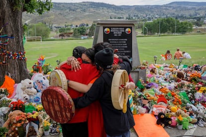 Algunas personas se abrazan frente a un memorial en honor a los niños del internado de Kamloops