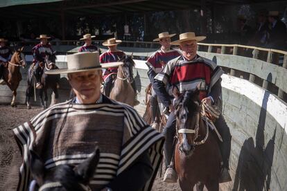 Cada jinete lleva su chupalla (sombrero de paja) y su chamanto mientras desfilan por el borde del ruedo.