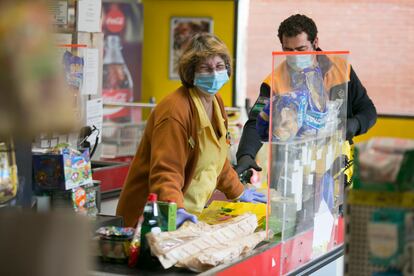 Una cajera atiende a un cliente en un supermercado en Manzanares el Real (Madrid).