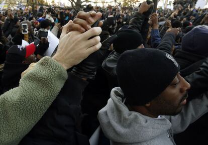 Una multitud de personas protesta cogiéndose y alzando sus manos.
