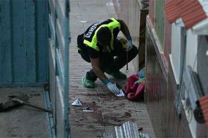 Un policía recoge pruebas en la vivienda de Alzira donde se produjo el tiroteo.