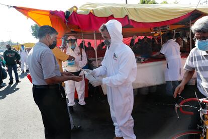 Personal de desinfección reparte gel antibacterial en un tianguis de Ciudad de México.