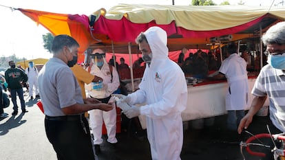 Personal de desinfección reparte gel antibacterial en un tianguis de Ciudad de México.