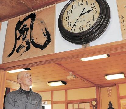 Sakano contempla el reloj de pared que ha vuelto a funcionar en su monasterio.