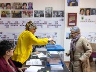 Una mujer vota en el colegio electoral de Malva (Zamora), adornado con los árboles genealógicos del pueblo.