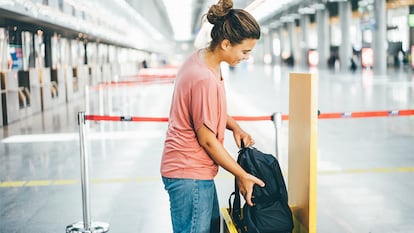 Una chica probando si su mochila se ajusta a las medidas de la aerolínea.