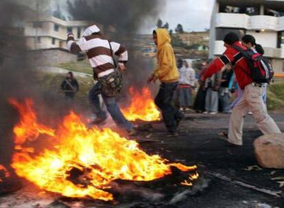 Varios peatones atraviesan una carretera bloqueada por una barricada en la localidad ecuatoriana de Cayambe.