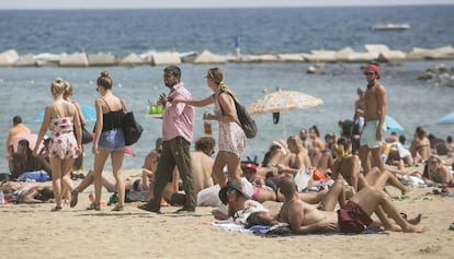 Una agent de la Guàrdia Urbana de paisà para a un venedor de mojitos aquest dimecres en la Barceloneta.